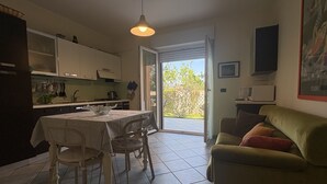 Et køkken med spisebord, stole, sofa og fjernsyn.