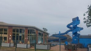 Un bâtiment doté de grandes fenêtres et d’une structure de toboggan aquatique bleue.