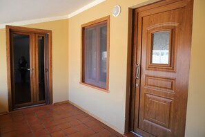 A hallway with a tiled floor, a wooden door with a glass panel, and a window with a wooden frame. - Sa Domu De Cadeddu - Three Bedroom Apartment, Sleeps 5 (Nurachi)