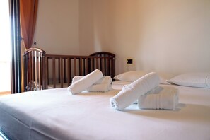 A hotel room with a bed, pillows, and a wooden crib. - Sa Domu De Cadeddu - Three Bedroom Apartment, Sleeps 5 (Nurachi)