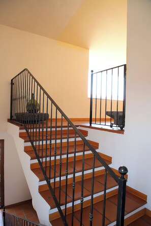 Eine Treppe mit hölzernen Stufen und schwarzen Metallgeländern, die zu einem Podest mit einer Steinsitzbank führt.