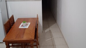 Un coin repas avec une table et des chaises en bois, une petite plante en pot et un sol carrelé.