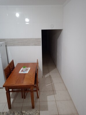 A dining area with a wooden table and chairs, a small potted plant, and a tiled floor.