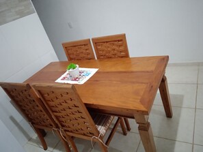 A wooden dining table with four chairs, a potted plant, and a placemat.