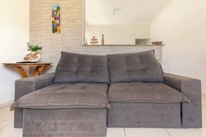 A grey sectional sofa with a wooden side table and a decorative vase. - House 50m from the beach with swimming pool (Itanhaém)