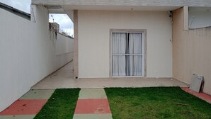 Un petit espace extérieur clos, doté d’un sol carrelé, d’une fenêtre avec des rideaux et d’un toit en béton.