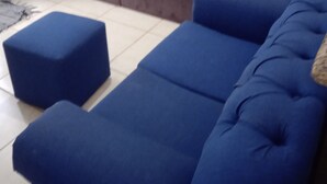 Un salon avec un canapé marron, un canapé bleu et un pouf bleu.