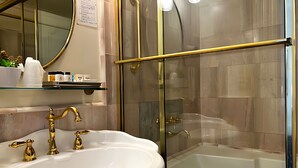 A bathroom with a white sink, gold faucets, a glass shower enclosure, and a bathtub. - Stylish Deluxe King Retreat in the Heart of Sacramento (Sacramento)