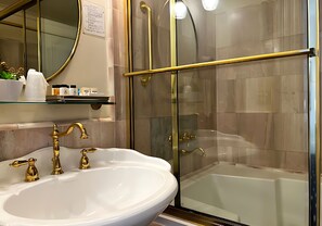 A bathroom with a white sink, gold faucets, a glass shower enclosure, and a bathtub. - Stylish Deluxe King Retreat in the Heart of Sacramento (Sacramento)