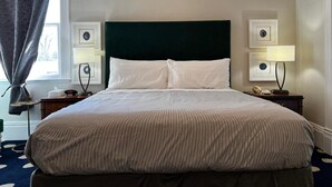 A neatly made bed with a dark headboard, two bedside lamps, and framed pictures on the nightstands. - Stylish Deluxe King Retreat in the Heart of Sacramento (Sacramento)