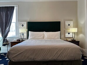 A neatly made bed with a dark headboard, two bedside lamps, and framed pictures on the nightstands. - Stylish Deluxe King Retreat in the Heart of Sacramento (Sacramento)