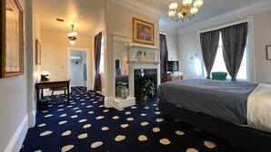 A hotel room with a polka dot carpet, a bed, a fireplace, a television, and a chandelier. - Stylish Deluxe King Retreat in the Heart of Sacramento (Sacramento)