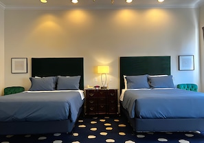 Habitación de hotel con dos camas, un aparador, una lámpara y una alfombra de lunares.