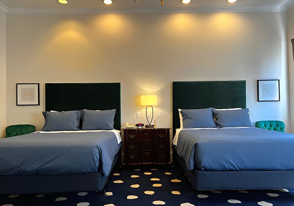 A hotel room with two beds, a dresser, a lamp, and a polka dot carpet. - Elegant Deluxe Two Queen Room Near Sacramento Attractions (Sacramento)
