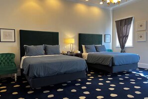 A hotel room with two beds, a green armchair, a patterned carpet, and a window with curtains. - Elegant Deluxe Two Queen Room Near Sacramento Attractions (Sacramento)