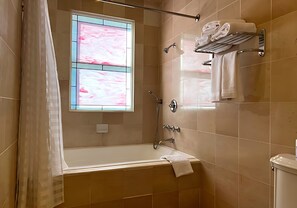 A bathroom with a bathtub, shower, and a window with pink curtains. - Elegant Deluxe Two Queen Room Near Sacramento Attractions (Sacramento)