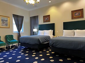 A hotel room with two beds, a green armchair, a chandelier, and artwork on the walls. - Elegant Deluxe Two Queen Room Near Sacramento Attractions (Sacramento)