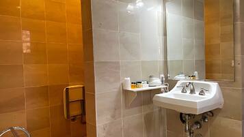 Un baño con lavamanos blanco, espejo y repisa con artículos de tocador.