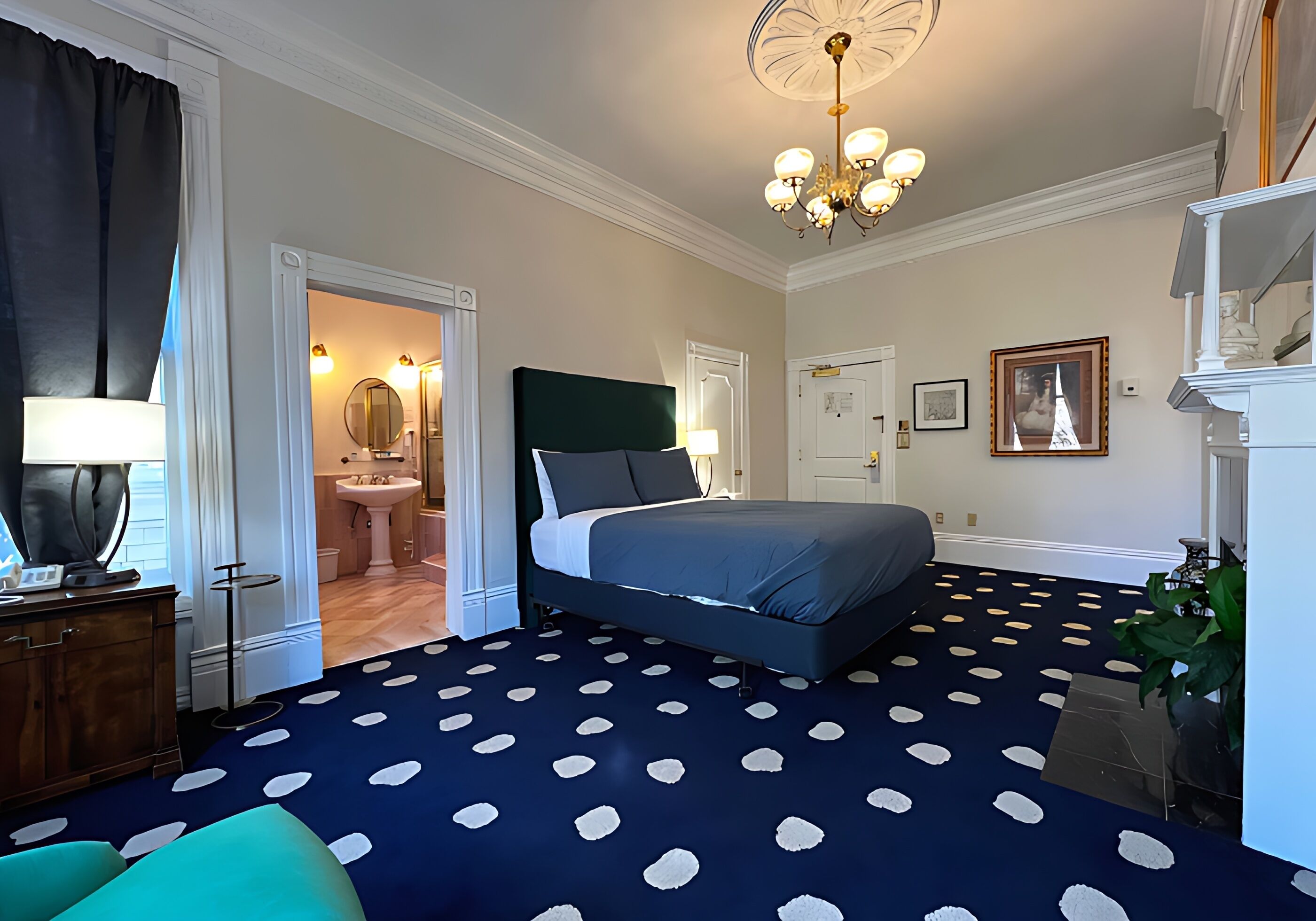 Quarto com cama, lustre, banheiro e escada.