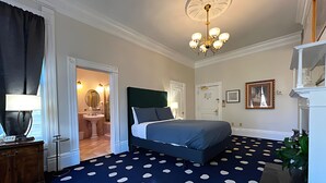 Een slaapkamer met een bed, een kroonluchter, een badkamer en een trap.
