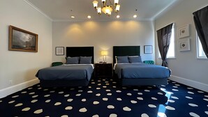Een hotelkamer met twee bedden, een kroonluchter, een schilderij en een gestipeld vloerkleed.