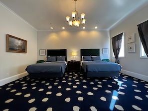 Habitación de hotel con dos camas, una araña, un cuadro y una alfombra de lunares.