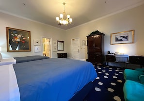 Habitación de hotel con una cama grande, un escritorio con computadora, una silla, un armario y una puerta que da a otra habitación.