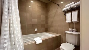 Een badkamer met bad, toilet en handdoekhouder.