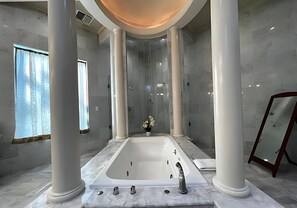Um banheiro moderno com uma banheira grande, piso de mármore e colunas.