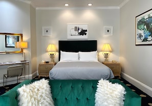 A hotel room with a large bed, two bedside tables with lamps, a desk with a chair, a mirror, and artwork on the walls. - Premium King Grand Suite Near Sacramento's Top Attractions (Sacramento)