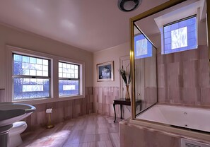 A bathroom with a bathtub, a toilet, a sink, a window, and a framed picture on the wall. - Elegant King Junior Suite at The Sterling Hotel Sacramento (Sacramento)