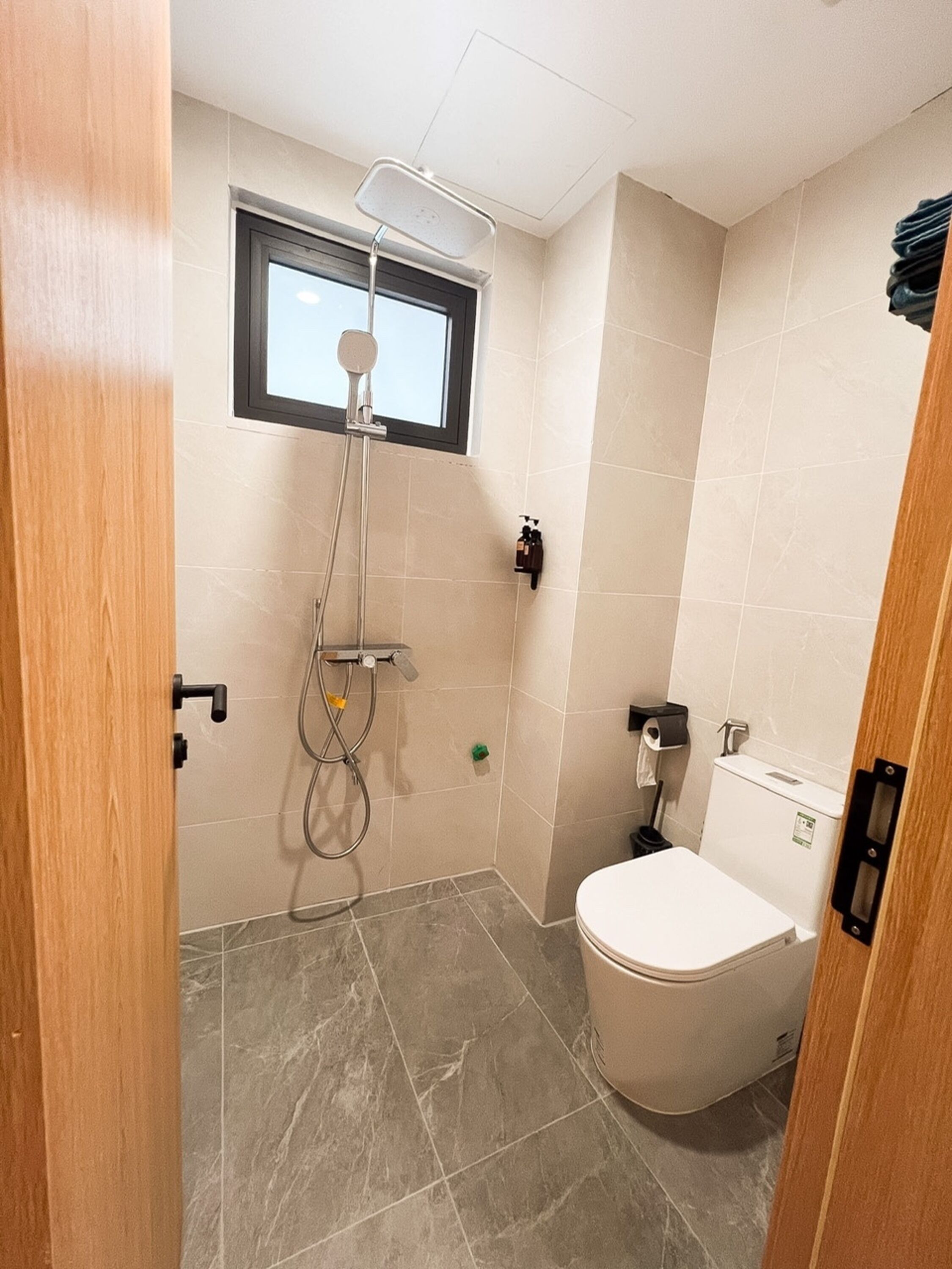 A bathroom with a shower, toilet, and a window.