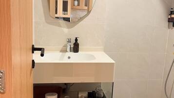 Ein Badezimmer mit einem weißen Waschbecken, einem Holzschrank, einem Spiegel und einem Fenster.