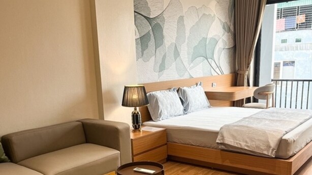Una camera d'albergo moderna con un letto, un divano, un tavolino e un comodino.