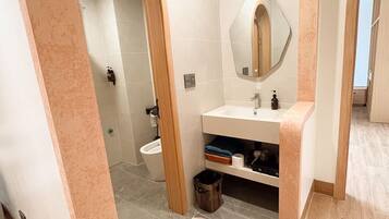 A modern bathroom with a wooden vanity, a toilet, and a shower area.