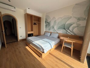 A bedroom with a bed, a desk, and a wardrobe.