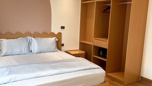 A bedroom with a bed, wooden wardrobe, and a nightstand.