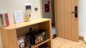 Una stanza con una reception in legno, una macchina per caffè, una libreria e una porta con la scritta '301'.