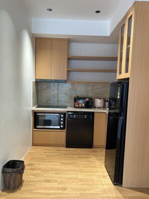 A compact kitchen with wooden cabinets, a microwave, a dishwasher, and a refrigerator.