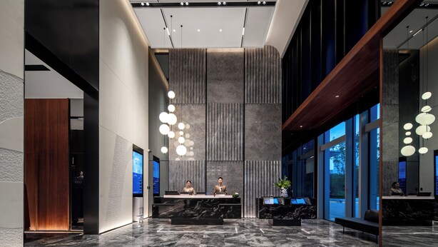 A modern reception area with marble flooring, a reception desk, and a large window.