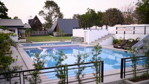 Un área de piscina moderna con vista despejada, sillas de descanso y una escalera que lleva a un edificio.