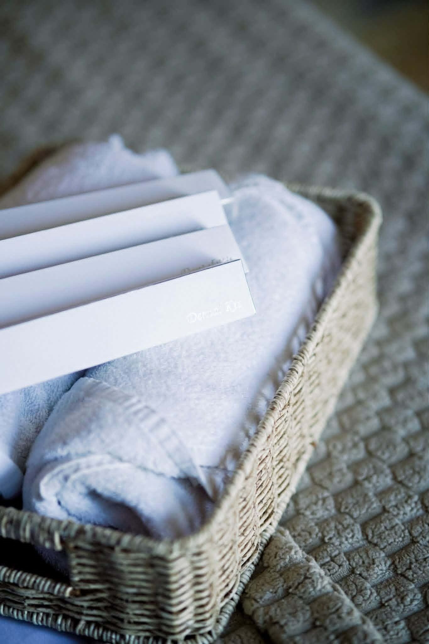 Una cesta de mimbre con toallas dobladas y una tarjeta blanca con texto.