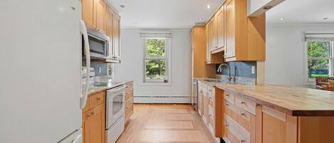 A modern kitchen with wooden cabinets, stainless steel appliances, and a large window.