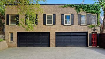 Un bâtiment en briques de deux étages, avec un garage et une porte rouge.