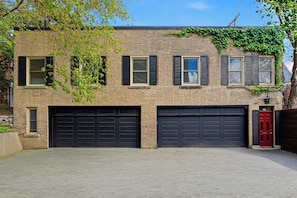 A two-story brick building with a garage and a red door.