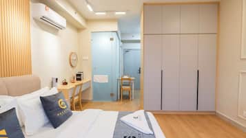 Ein Hotelzimmer mit Bett, Schreibtisch, Stuhl, Kleiderschrank und Klimaanlage.