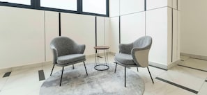 A modern room with two grey upholstered chairs, a small round table, and a grey carpet. - Astrum Ampang by Guestonic (Kuala Lumpur)