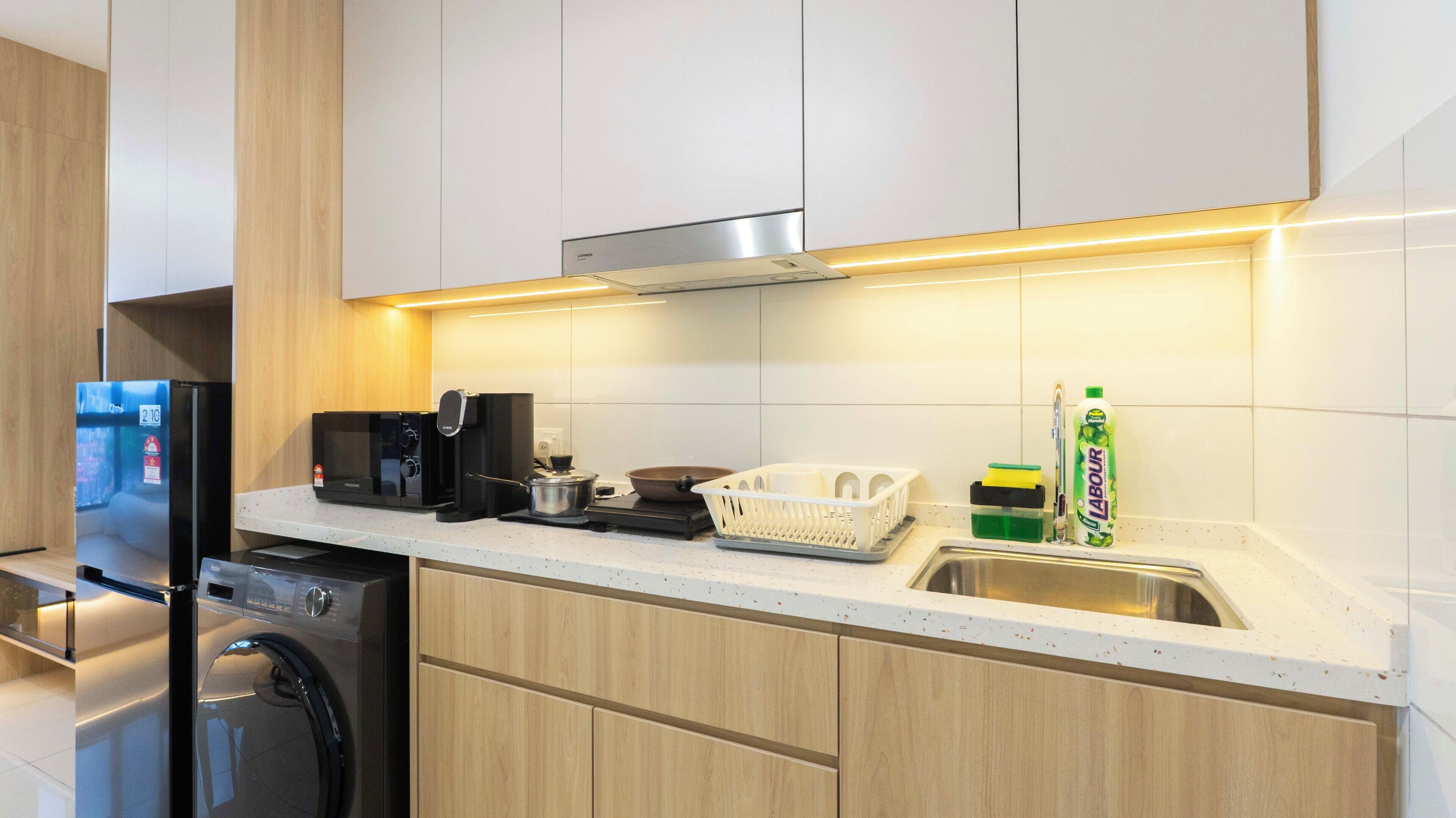 Una cocina moderna con lavavajillas integrado, cafetera y un lavabo con escurreplatos.