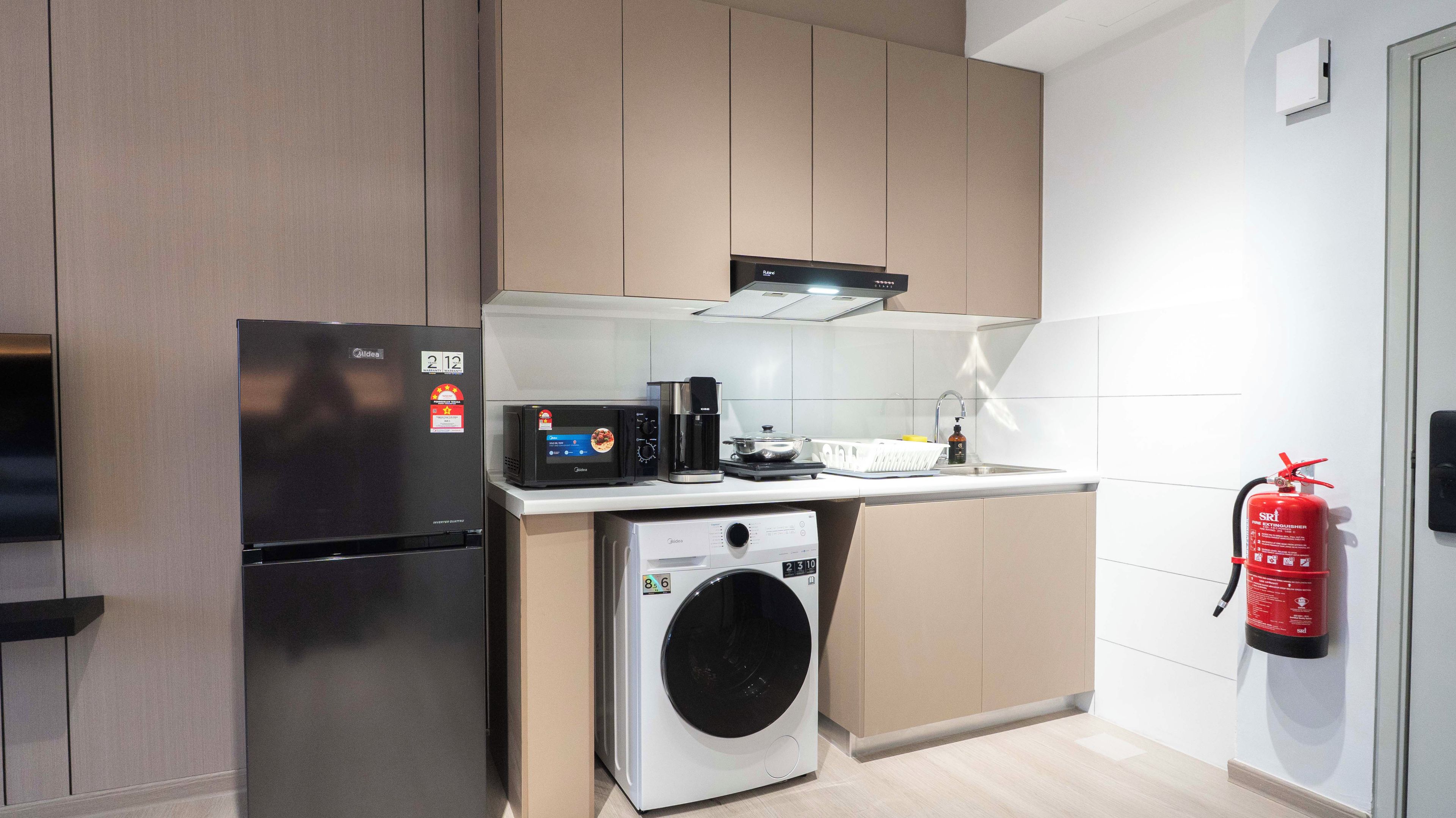 Een compact keukenhoekje met een ingebouwde wasmachine, een koffiezetapparaat en een magnetron.