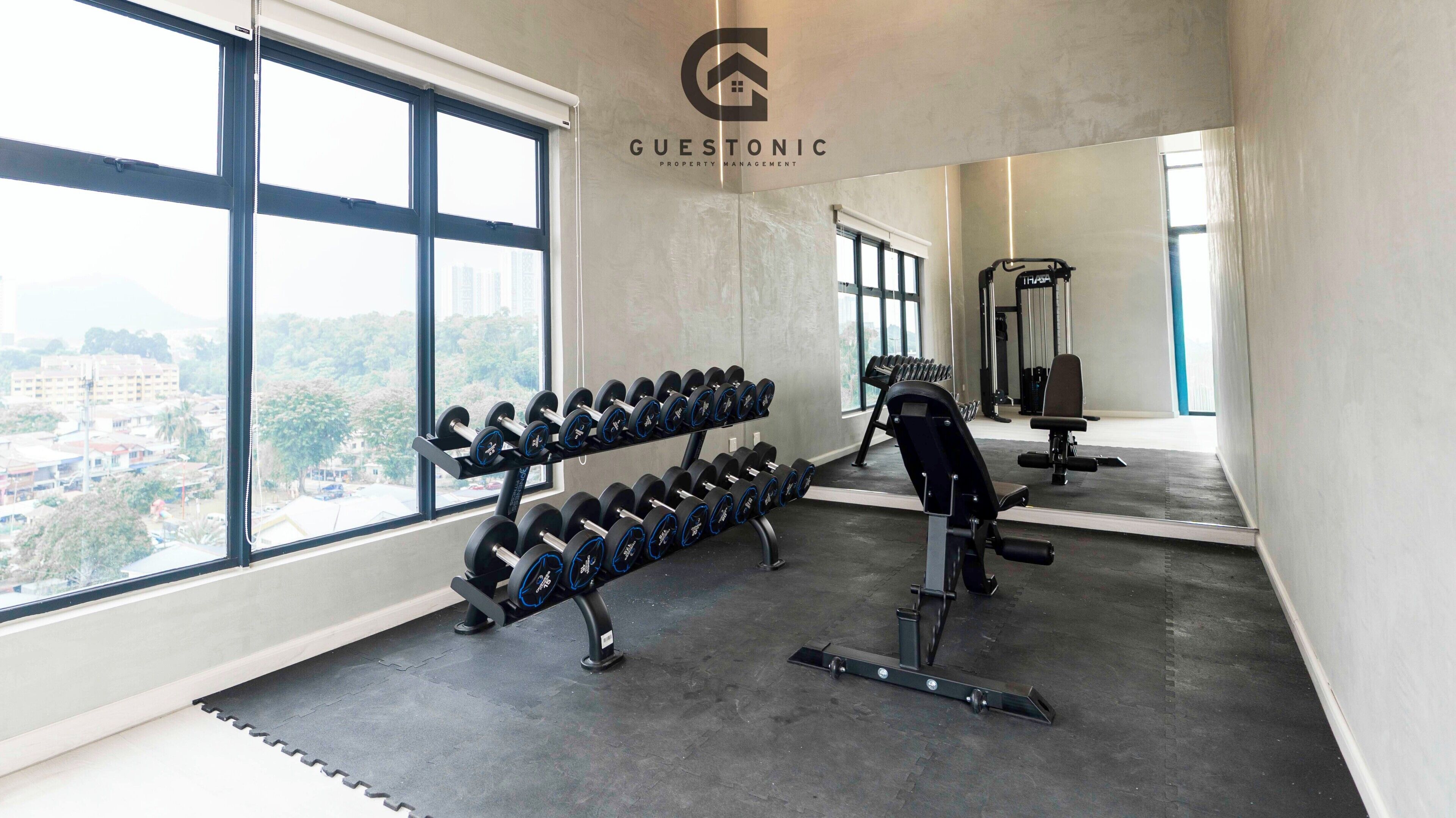 Un gimnasio con mancuernas, una prensa de banca y una cinta de correr.